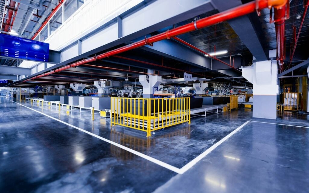 Real industrial appliance-recycling processing facility used to illustrate how thermal cameras may identify abnormal heating; hotspot overlay is illustrative, not measured.